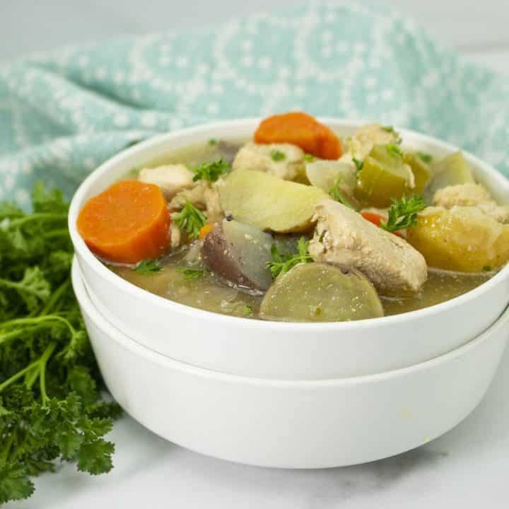 Easy slow cooker chicken stew in a white bowl with parsley on the side