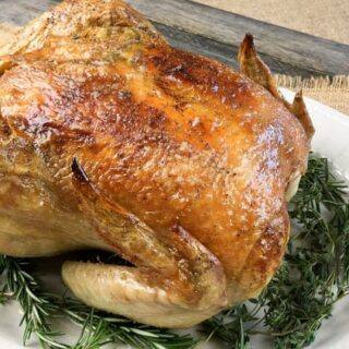 keto chicken sitting on herbs on a white plate on a countertop
