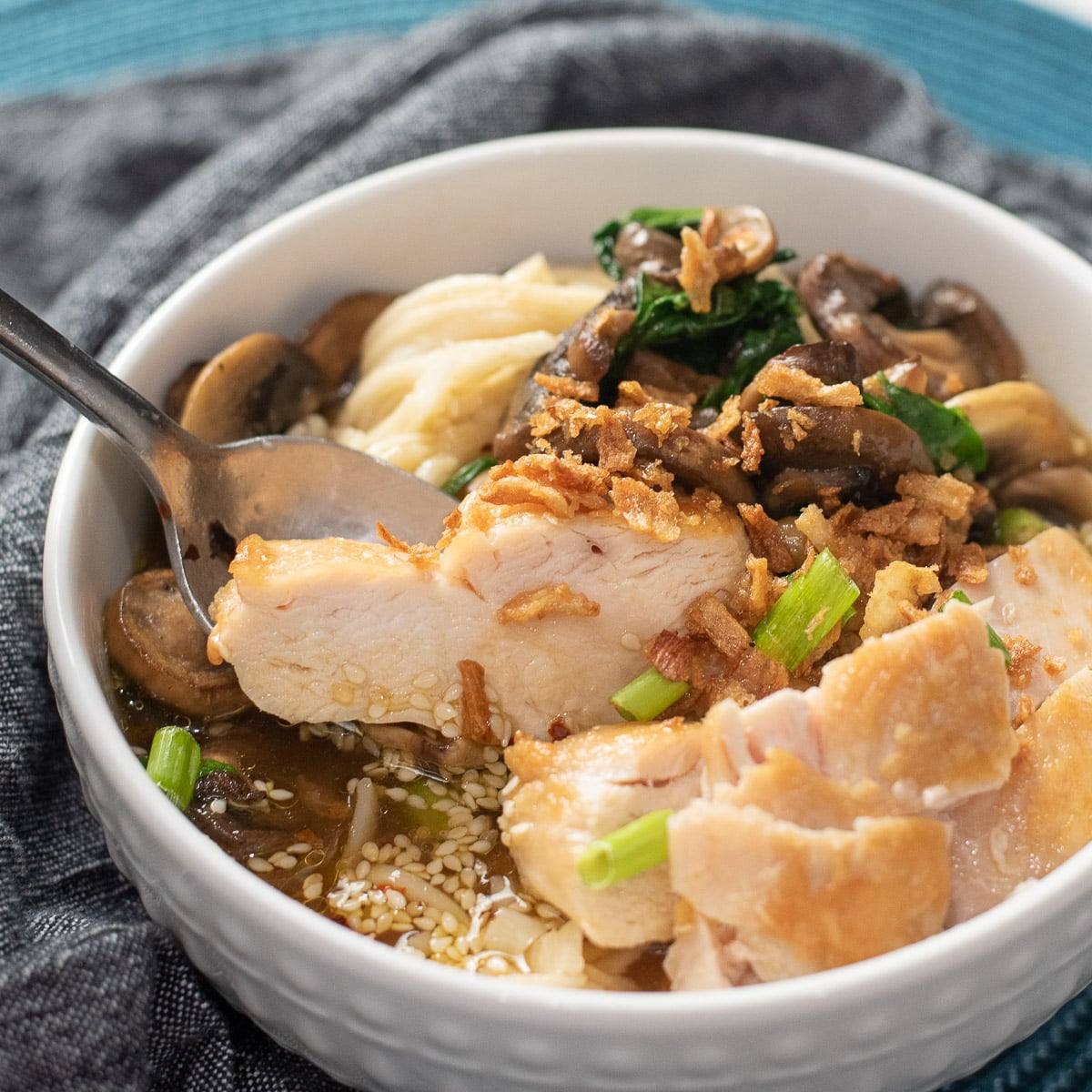 Bowl of easy chicken ramen with sliced chicken, mushrooms, spinach, and noodles