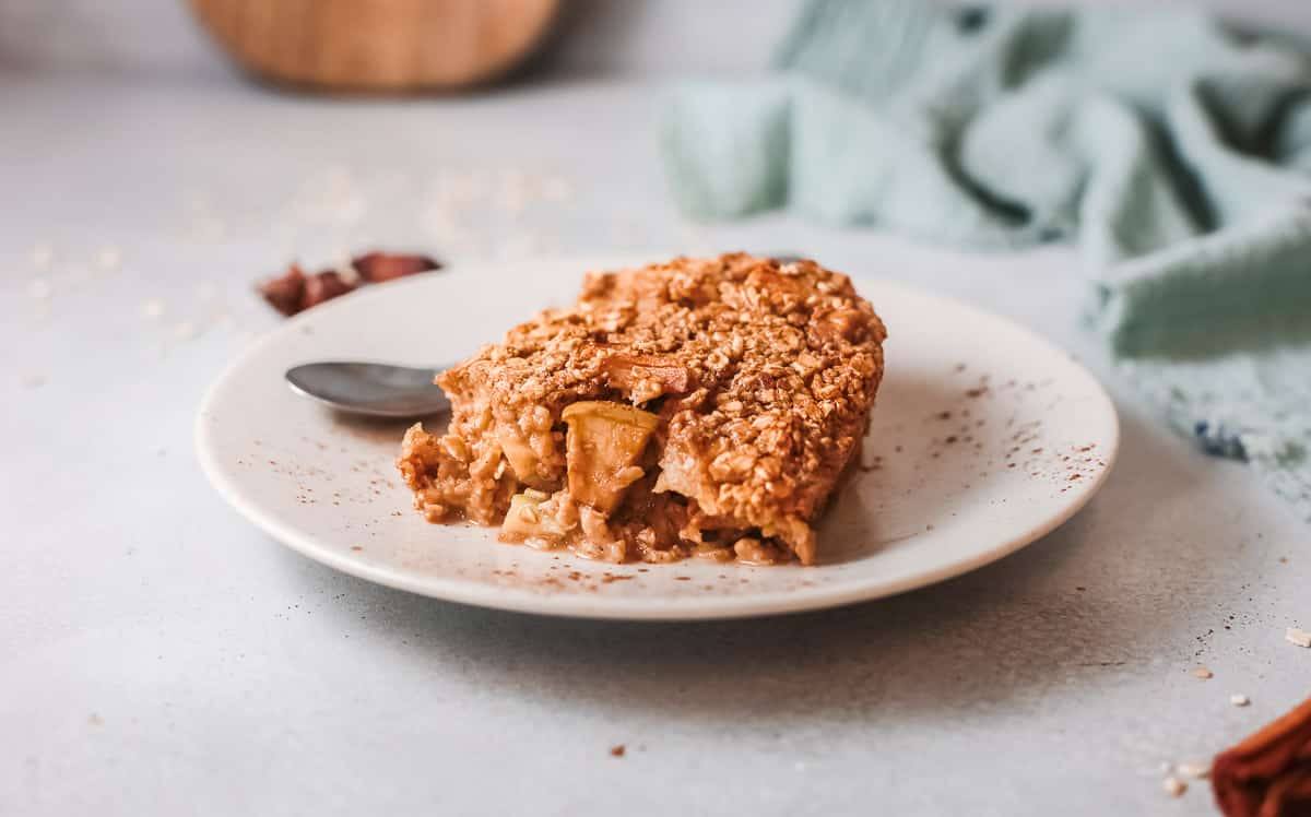 Slice of apple cinnamon baked oatmeal with chunks of apple on a plate with a spoon