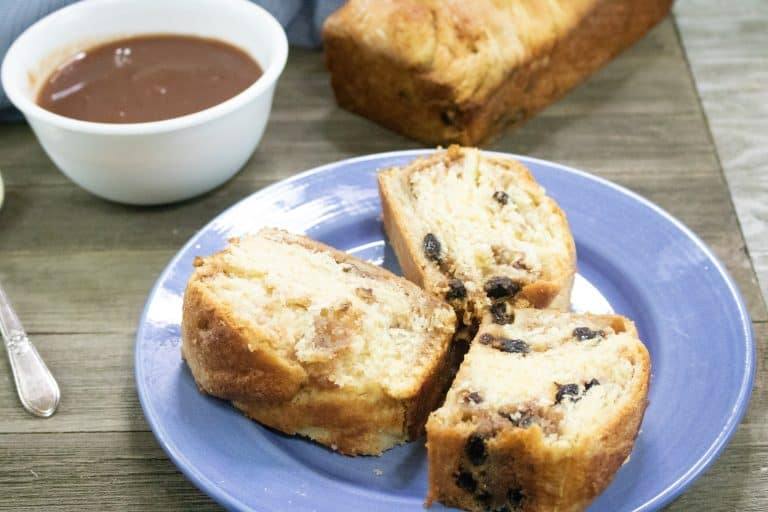 3 slices of Apple Butter Coffee Cake served on a blue plate in front of a full loaf and small white bowl of apple butter