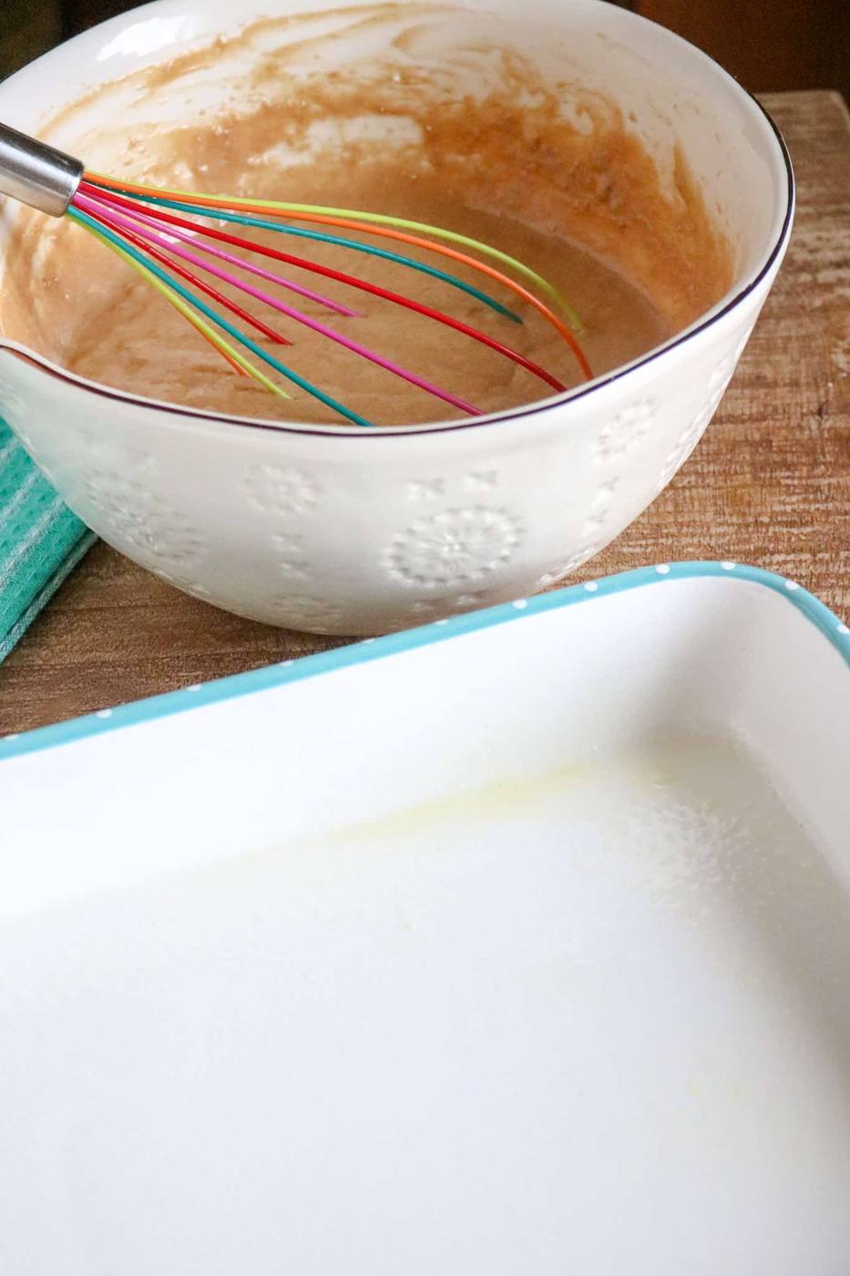 Mixed spice cake batter in a bowl next to a greased 9x13 baking pan