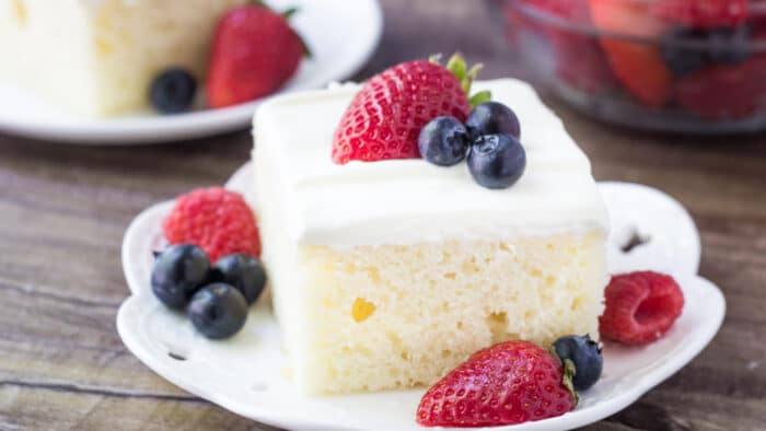 This berries and cream sheet cake is perfect for summer. It's a delicious vanilla sheet cake with a soft cake crumb. Then it's topped with a cream cheese topping & fresh berries.