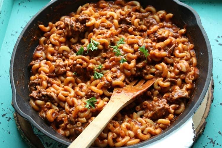 Overhead view of chili mac in a cast iron skillet with a wooden spoon