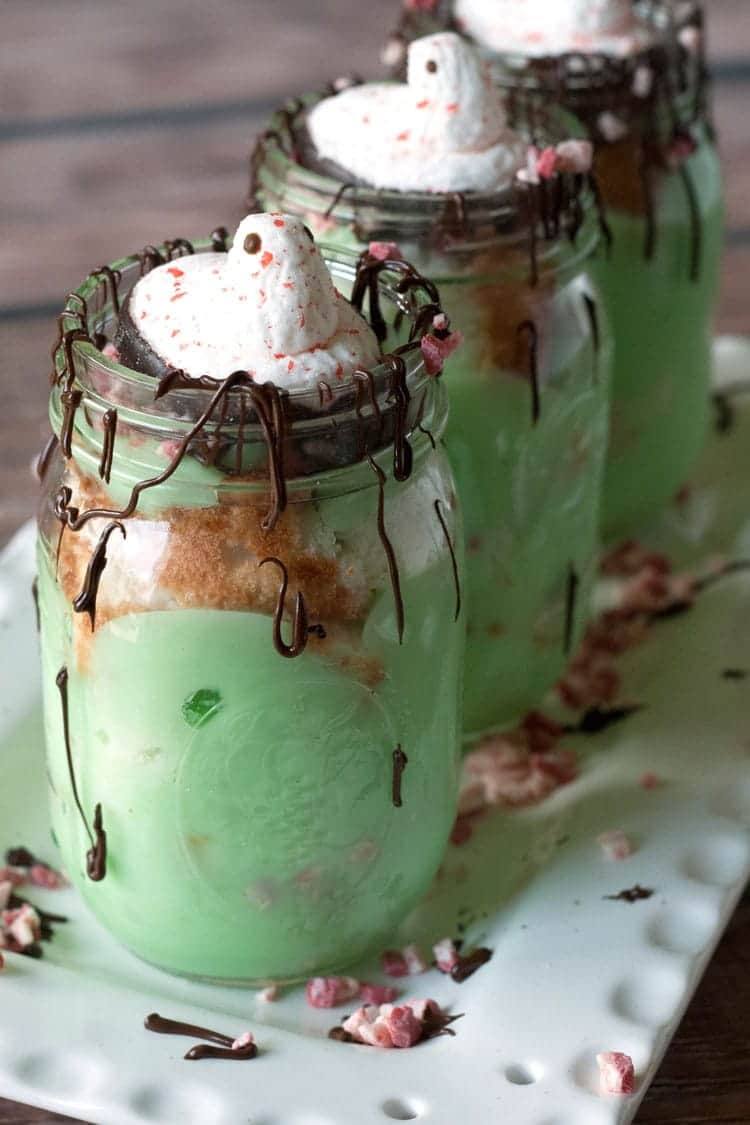 Pistachio trifle in a mason jar topped with a chocolate-dipped candy cane Peep