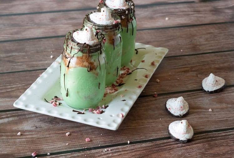 Layers of pistachio pudding, angel food cake and crushed peppermint in mason jars