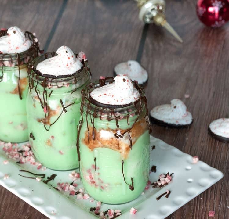 Three pistachio trifles on a white platter with Christmas ornaments in the background