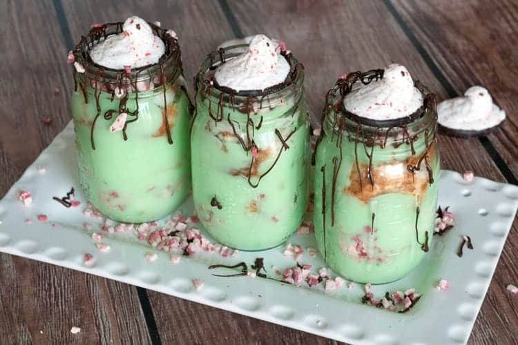 Row of pistachio trifles in mason jars drizzled with chocolate and topped with Peeps