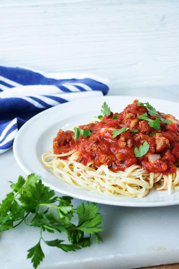 meat pasta sauce on top of noodles on white plate