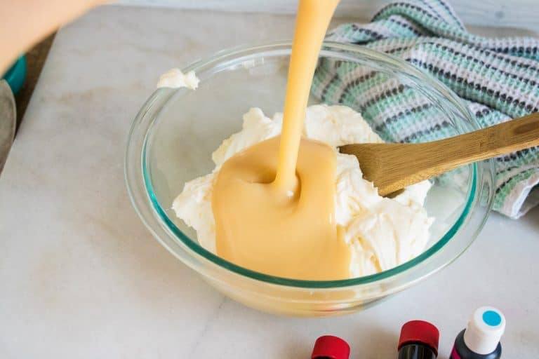 Whipped cream in bowl with sweetened condensed milk being poured on top.