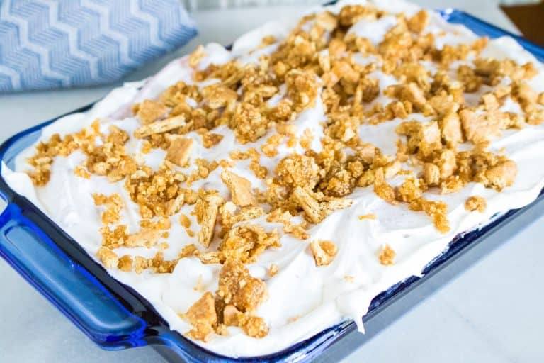completed blueberry poke cake with whipped topping and graham cracker brown sugar streusel topping