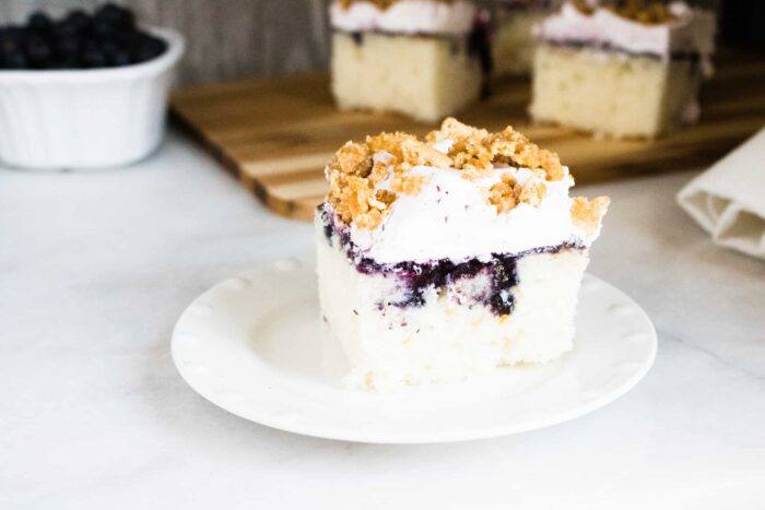 A slice of Blueberry Buckle Poke Cake served on a white plate