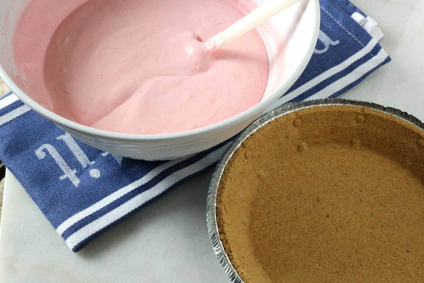 pie filling mixture in a bowl sitting next to the pre-made graham cracker pie crust