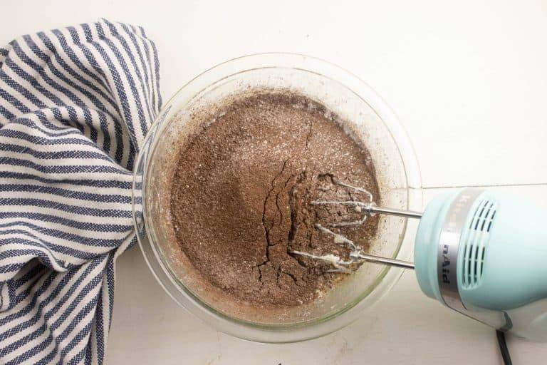 dry ingredients being combined with wet ingredients for making cheesecake brownies