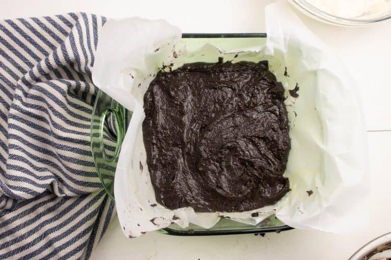 brownie batter for the Cheesecake Brownies recipe spread in the bottom of a square baking pan