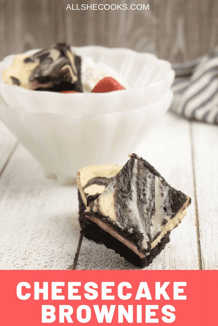 one portion of cheesecake brownies served in a white bowl and two brownies in front of the bowl