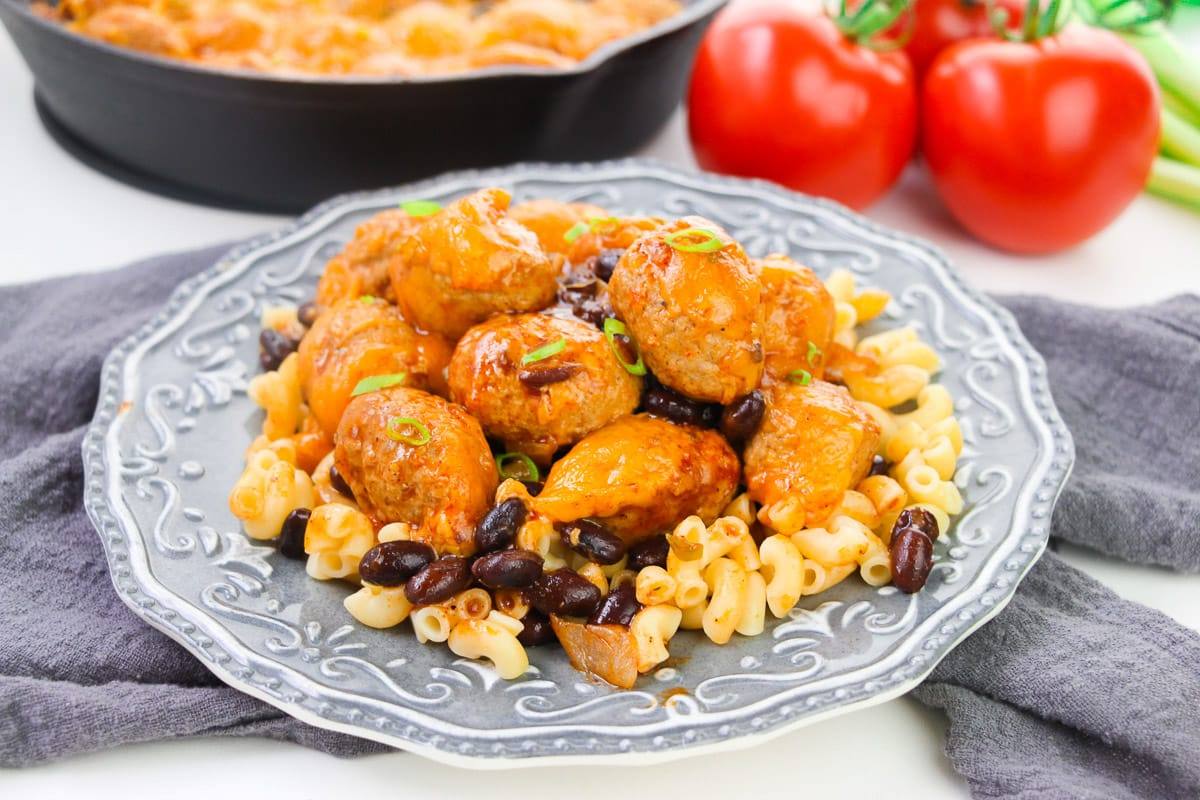 cheesy enchilada meatballs served over macaroni pasta on gray textured plate