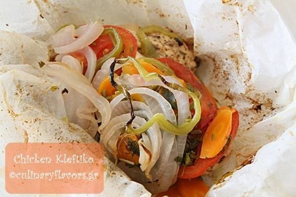 Close-up of chicken kleftiko with feta, tomatoes, carrots, onions and green peppers baked in parchment paper