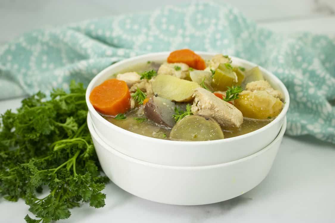 Easy slow cooker chicken stew in a white bowl with parsley on the side