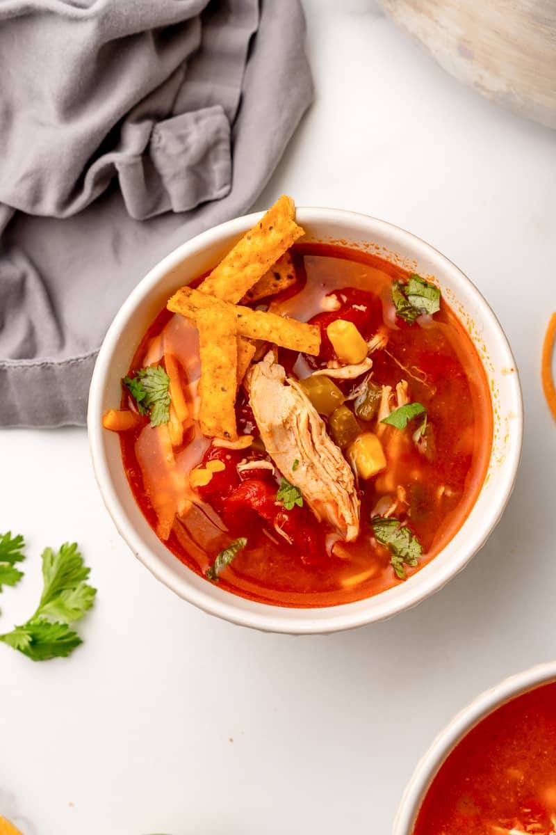 Overhead view of southwest chicken soup with shredded chicken, corn and tortilla strips