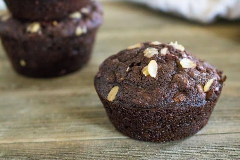 Completed Chocolate Chocolate Chip Oatmeal Muffins sitting on wood table.