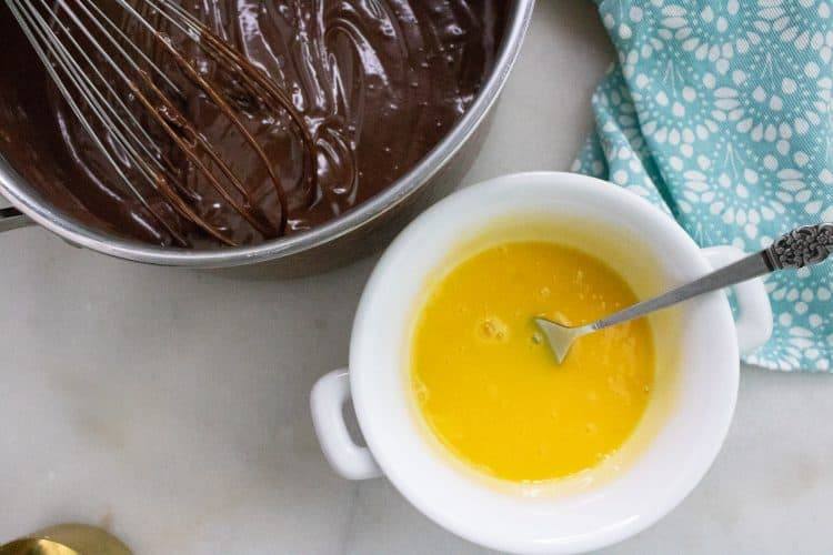 egg yolks in small white bowl with bowl of chocolate pie filling to the top left