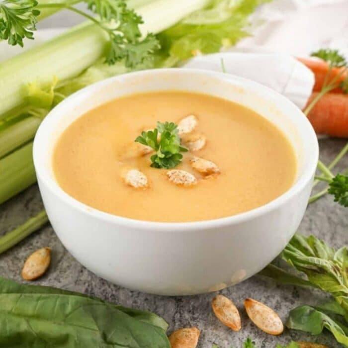 Bowl of copycat Panera autumn squash soup topped with toasted pumpkin seeds and parsley