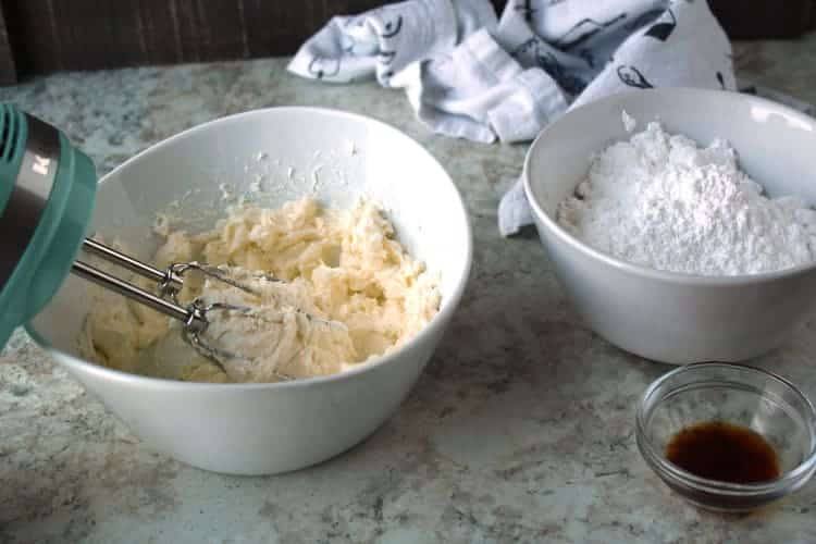 easy cream cheese frosting ingredients being beaten in a white bowl with a mixer