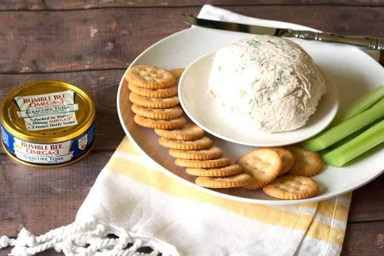 Cream cheese tuna dip with crackers and celery on a white serving plate
