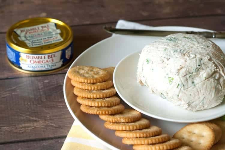 Cream cheese tuna dip ball on a plate with crackers, a knife and a can of albacore tuna