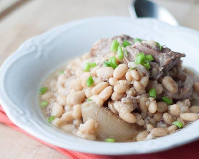 Close-up of navy beans, tender ham and onion in a white bowl
