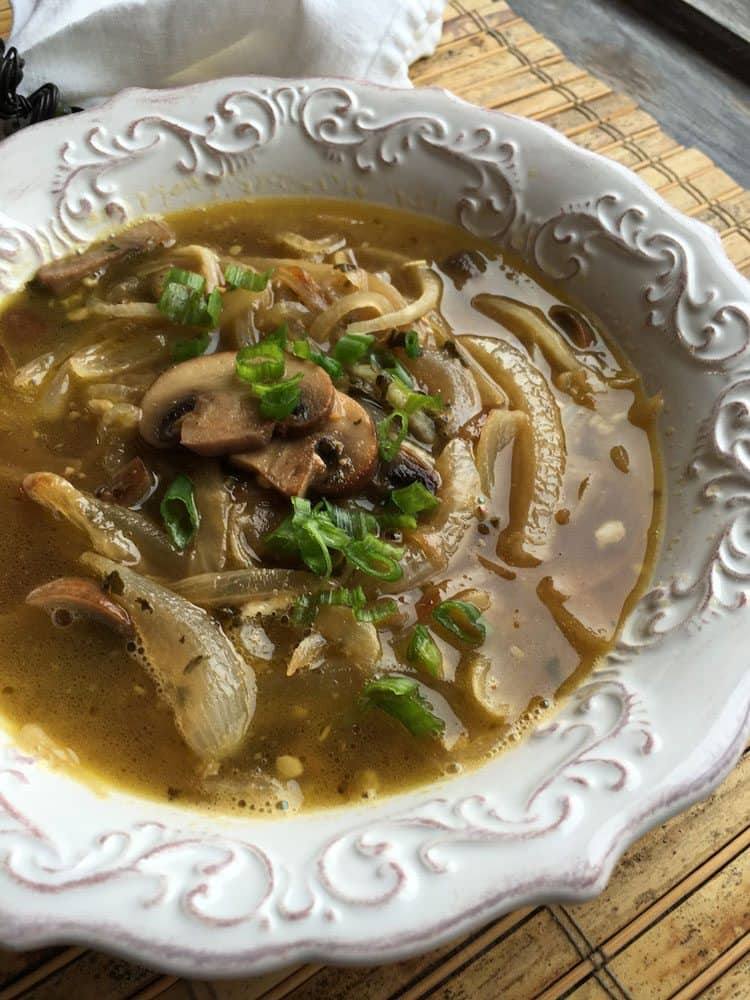 Close-up of radish noodle soup with sliced mushrooms and green onions