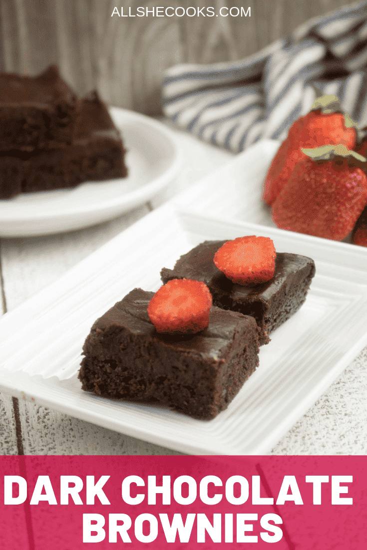 2 plated dark chocolate brownies on a white plate with a stack of brownies in the background