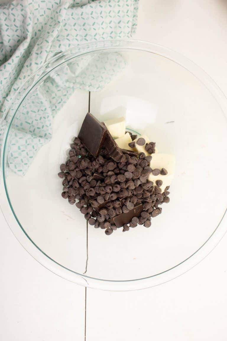 Semi-sweet chocolate chips, dark chocolate and butter for Dark chocolate brownies in clear glass bowl.