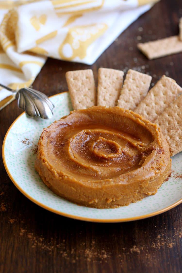Dessert pumpkin hummus swirled on a plate with graham crackers and a dusting of pumpkin pie spice