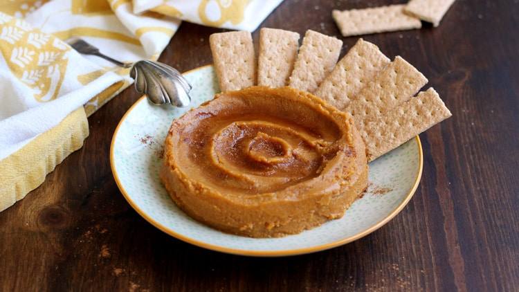 Plate of dessert pumpkin hummus served with graham crackers on a wooden table