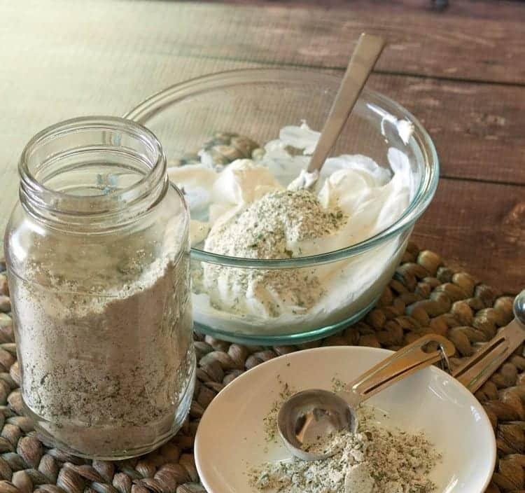 ranch dressing mix in a ball jar next to a clear glass bowl with sour cream and mix combined