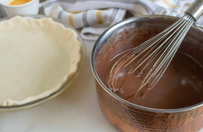 Chocolate pie mixture in saucepan with unbaked pie crust beside