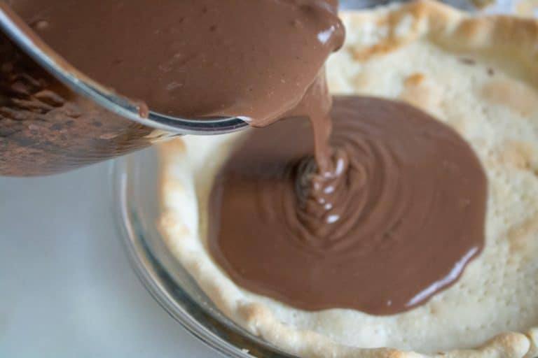 Chocolate cream pie mixture being poured into a pre-baked pie crust