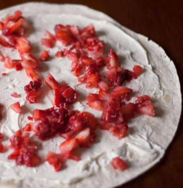Flour tortilla spread with cream cheese and topped with chopped strawberries and raspberries