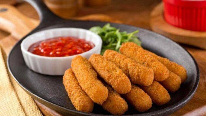 fried mozzarella sticks with marinara dipping sauce in a cast iron pan