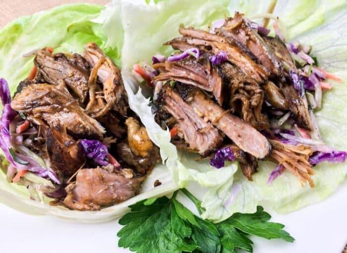 easy keto lettuce wraps containing pulled pork and red cabbage inside a piece of lettuce