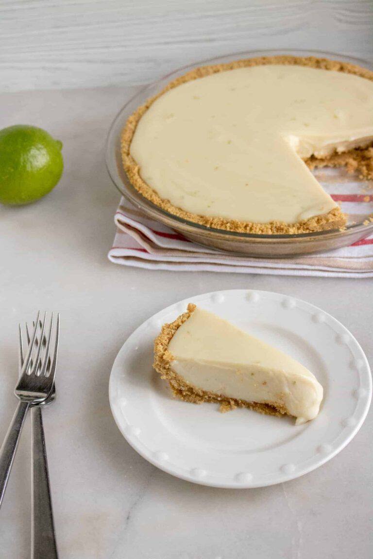 One slice of Quick and Easy Key Lime Pie cut from the pie and served on a white dessert plate with a silver fork