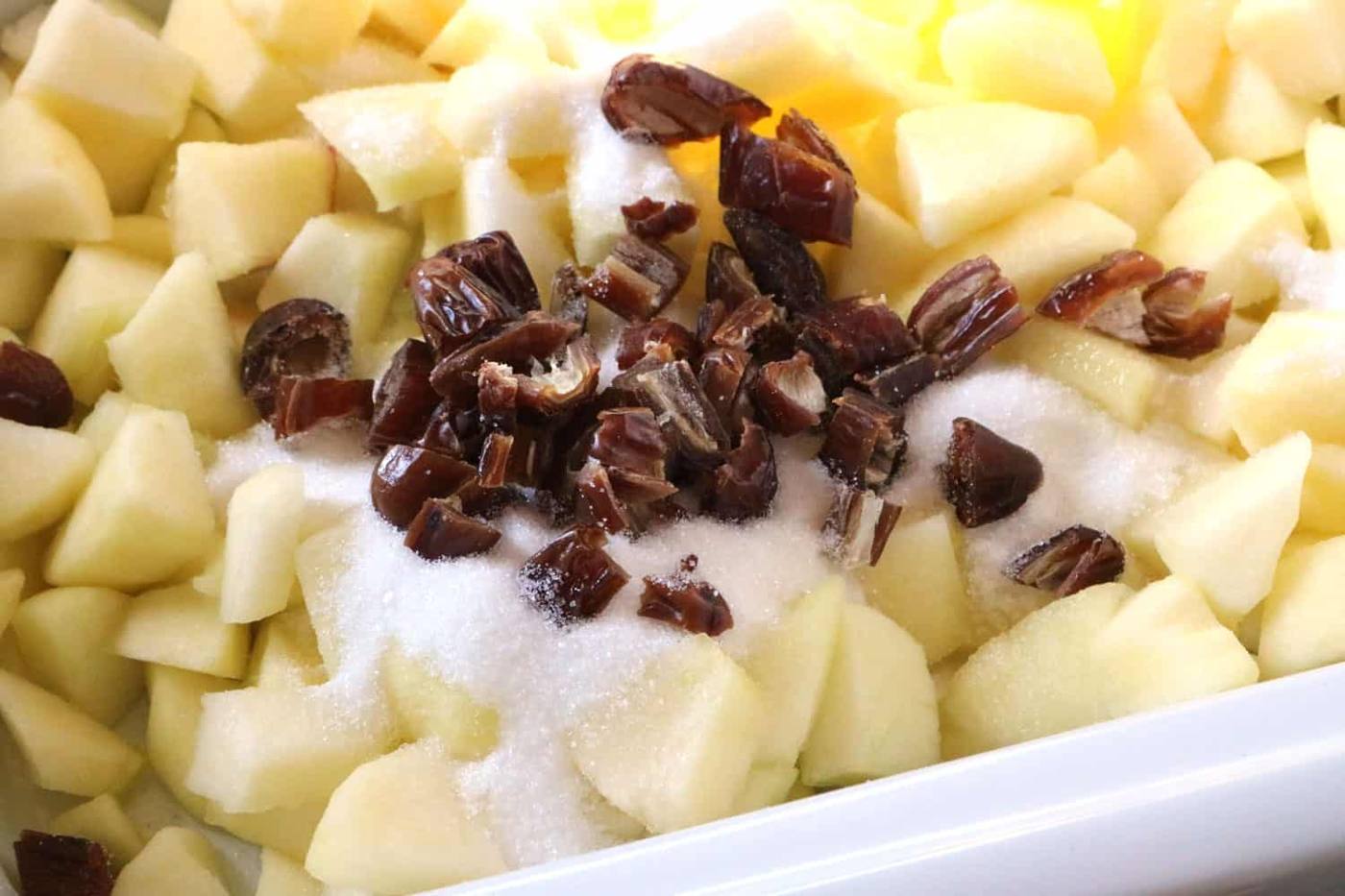 Chopped dates added to apples and sugar in slow cooker for bread pudding recipe.