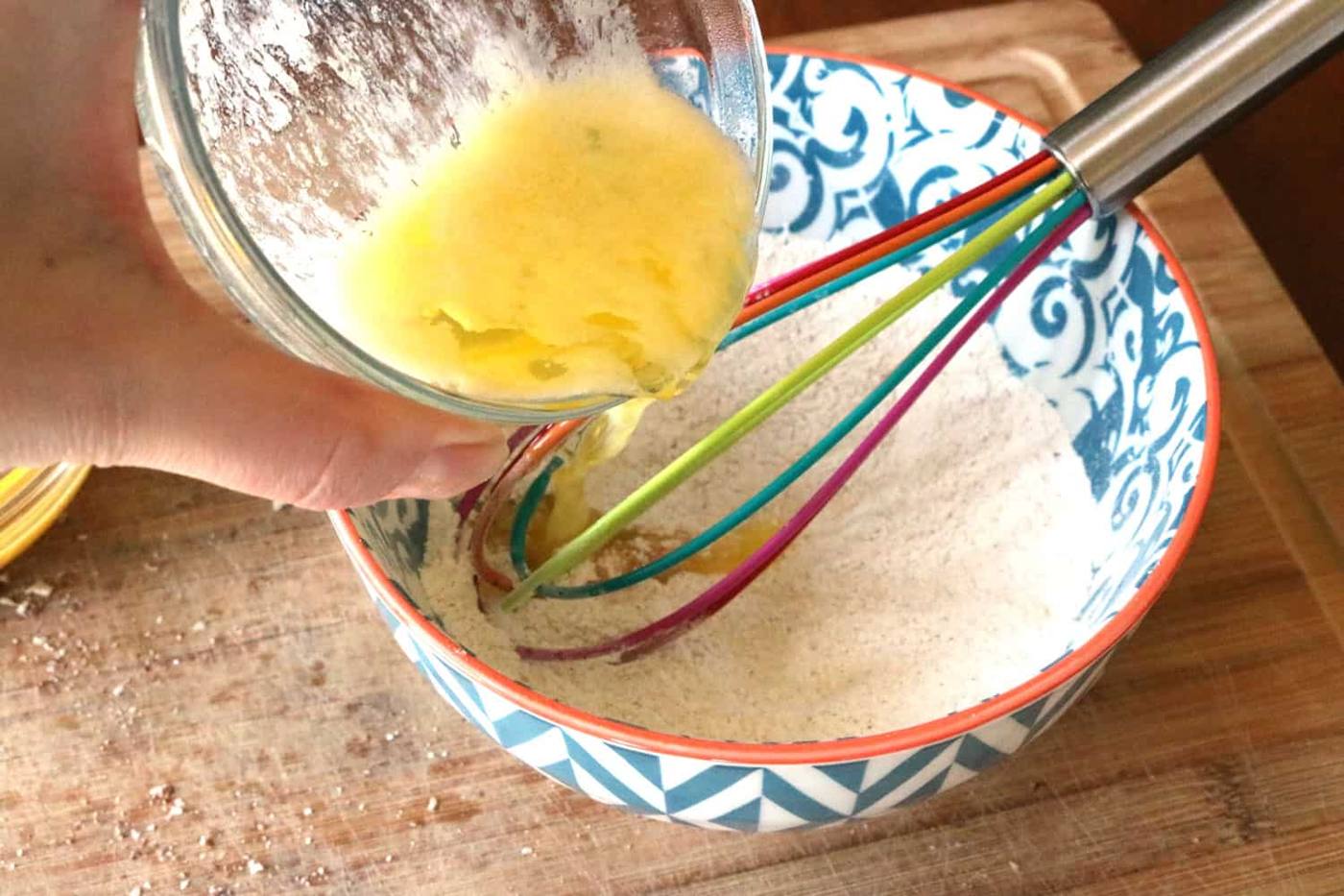 Melted butter added to the dry bread pudding ingredients in bowl.