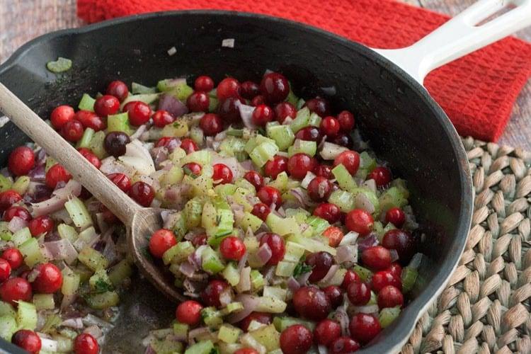 Cranberry stuffing mixture sauteing in a skillet with celery and onions on the stovetop