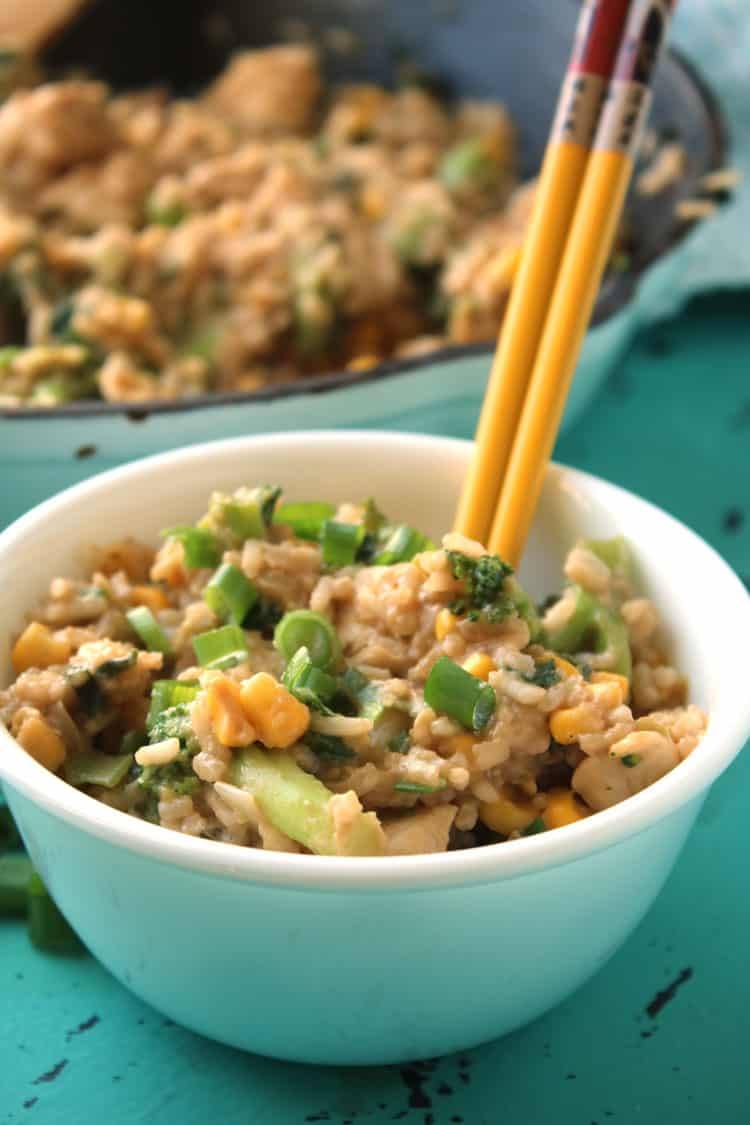 two yellow and red chopsticks sitting in a bowl of chicken fried rice