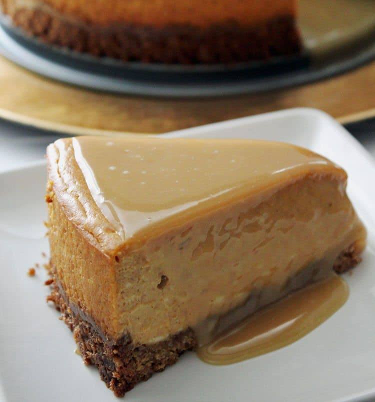 Slice of pumpkin maple cheesecake with maple glaze dripping onto a white plate