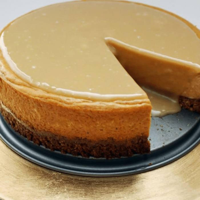 Pumpkin maple cheesecake with a slice cut out, showing the pecan oat crust and maple glaze