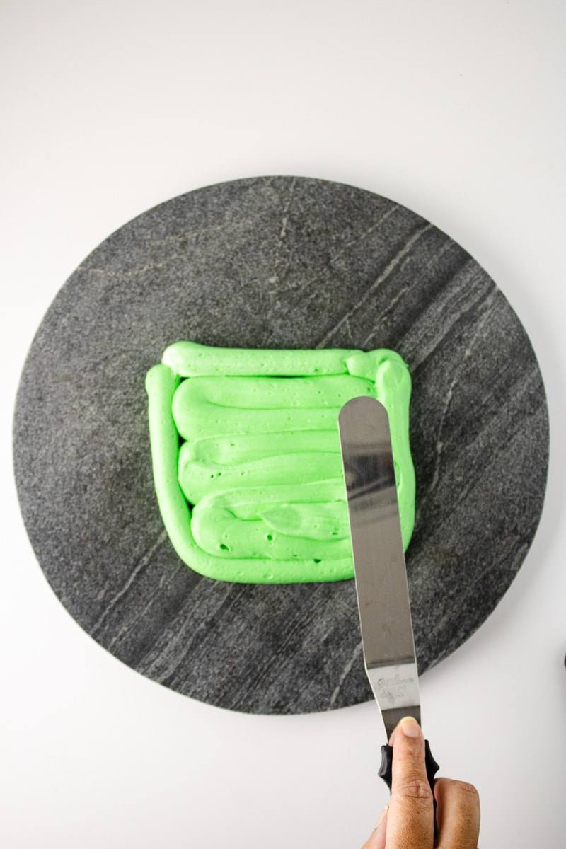 Green buttercream piped and smoothed into a Frankenstein face shape on a serving board